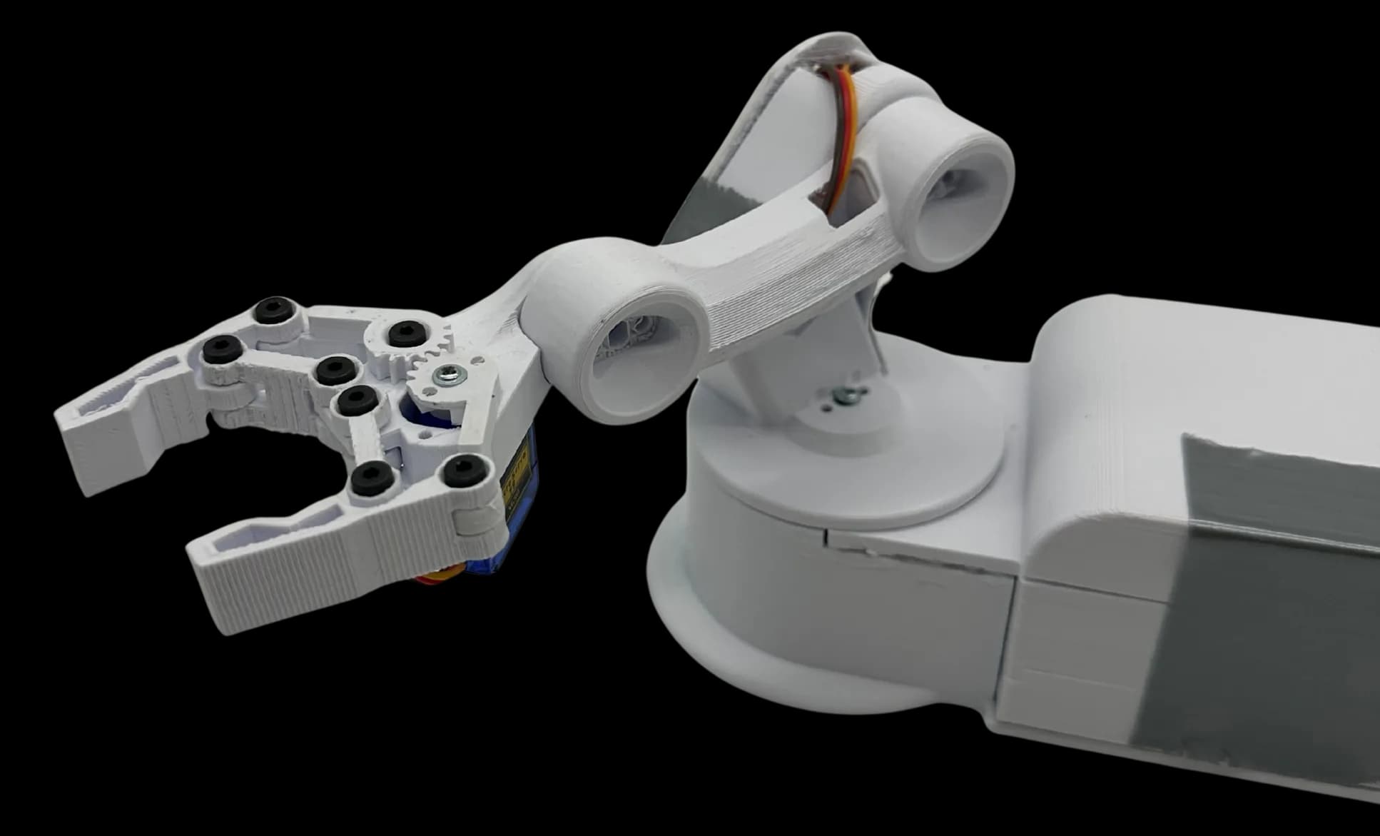 The finished robotic arm as a cut-out: a white PLA two-finger claw with black screw heads and a blue micro servo, a dog-bone forearm link with orange servo wires, and the turntable base running off the right edge